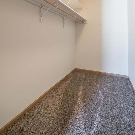 Thumbnail 10 of 11 A room with a carpeted floor and a white wall.