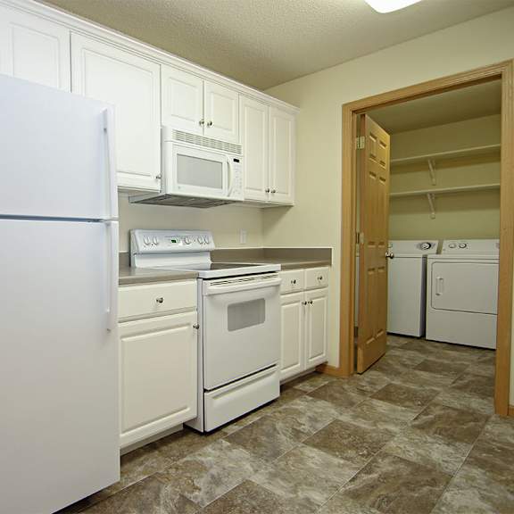 Thumbnail 3 of 12 A kitchen with white appliances and cabinets.