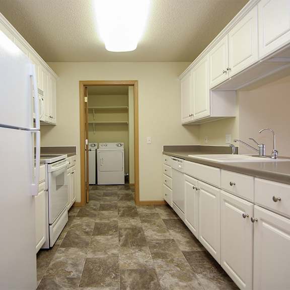 Thumbnail 2 of 12 A kitchen with white appliances and cabinets.