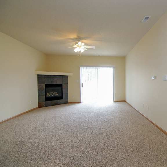Thumbnail 9 of 12 A room with a fireplace and a ceiling fan.
