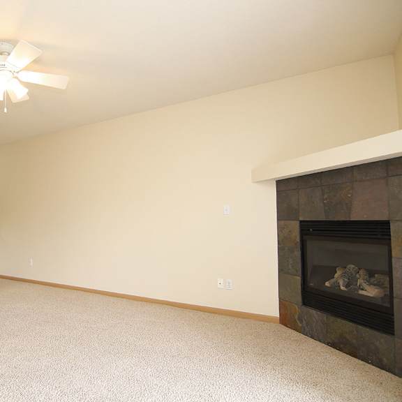 Thumbnail 10 of 12 A living room with a fireplace and a ceiling fan.