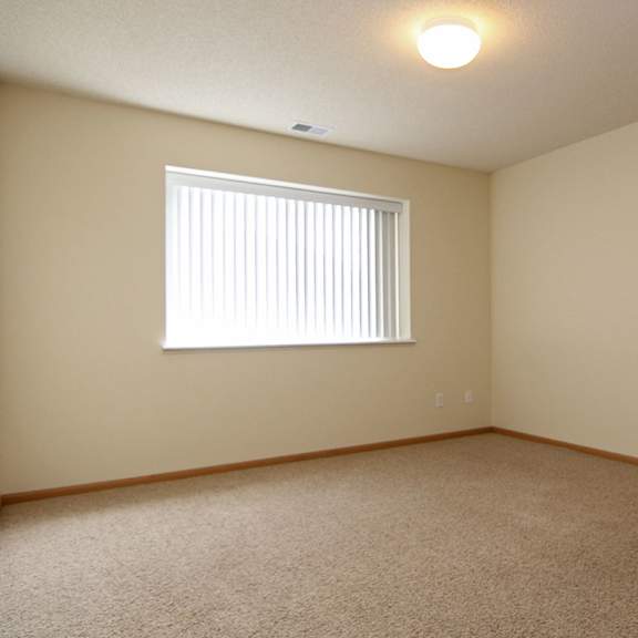 Thumbnail 11 of 12 A room with a carpeted floor and a window with blinds.