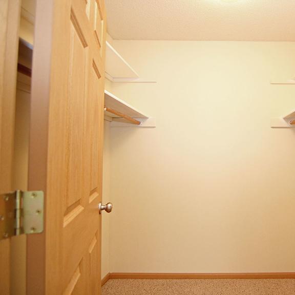 Thumbnail 12 of 12 A hallway with a door on the left and a shelf on the right.