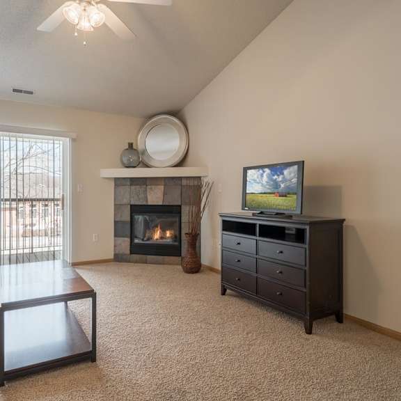 Thumbnail 5 of 20 A living room with a fireplace, television, and a couch.