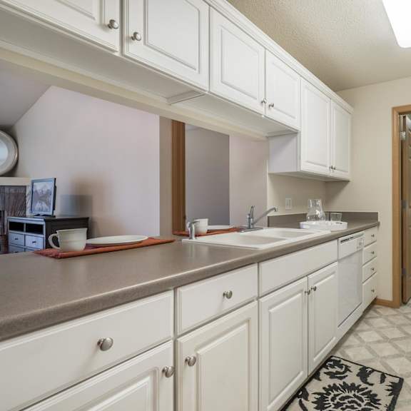 Thumbnail 9 of 20 A kitchen with white cabinets and a black and white rug on the floor.