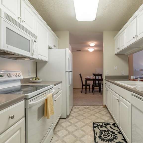 Thumbnail 8 of 20 A kitchen with white appliances and cabinets.