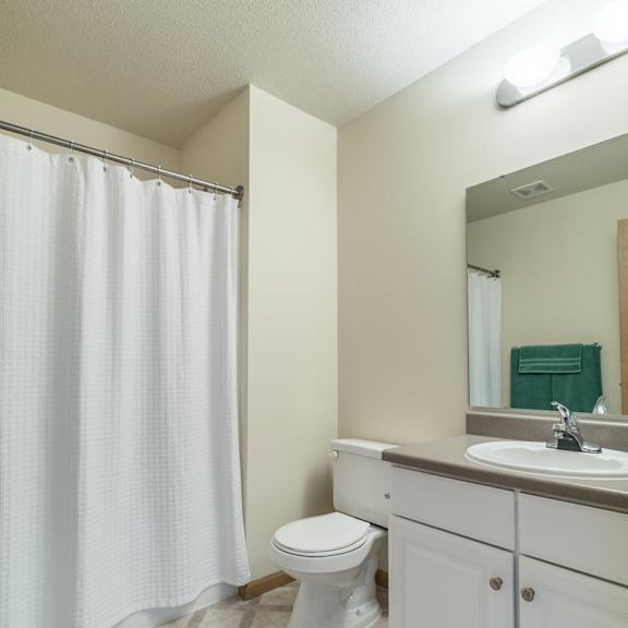 Thumbnail 14 of 20 A white toilet sits in a bathroom with a white shower curtain.