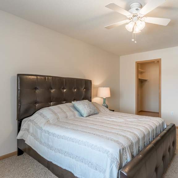Thumbnail 16 of 20 A bedroom with a bed, a ceiling fan, and a lamp.