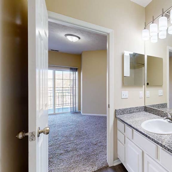 Thumbnail 17 of 28 a bathroom attached to the primary bedroom with a vanity sink featuring granite countertops, white cabinets, and large mirrors under modern light fixtures
