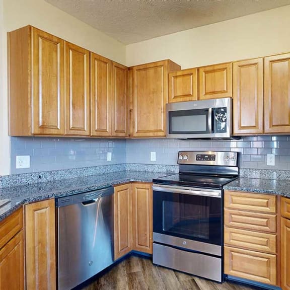 Thumbnail 10 of 28 a kitchen with granite countertops, wooden cabinets, a tile backsplash, and stainless steel appliances