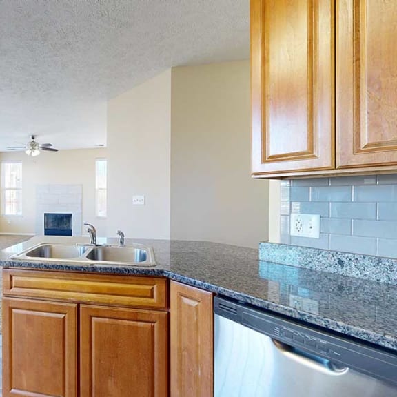 Thumbnail 11 of 28 a kitchen with granite countertops, a tile backsplash, wooden cabinets, and a stainless steel sink