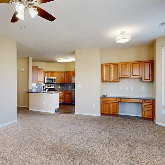 Thumbnail 8 of 28 an open-concept living and dining area with carpeted flooring, a ceiling fan, and a built in desk with storage