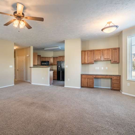 Thumbnail 5 of 16 A spacious living room with a ceiling fan and carpeted floor.