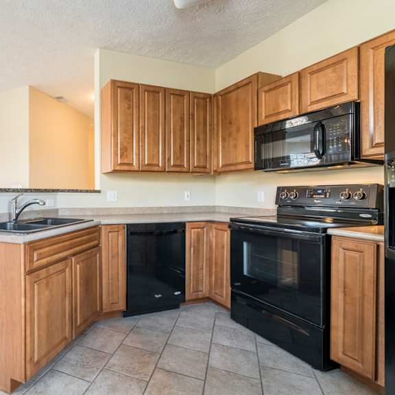 Thumbnail 6 of 16 A kitchen with black appliances and wooden cabinets.