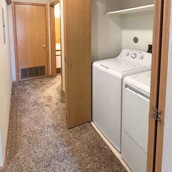 Thumbnail 7 of 11 a hallway with a laundry closet with a full sized washer and dryer