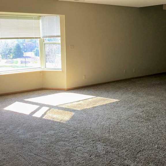 Thumbnail 5 of 11 a living room with a carpeted floor and a window letting in sunlight
