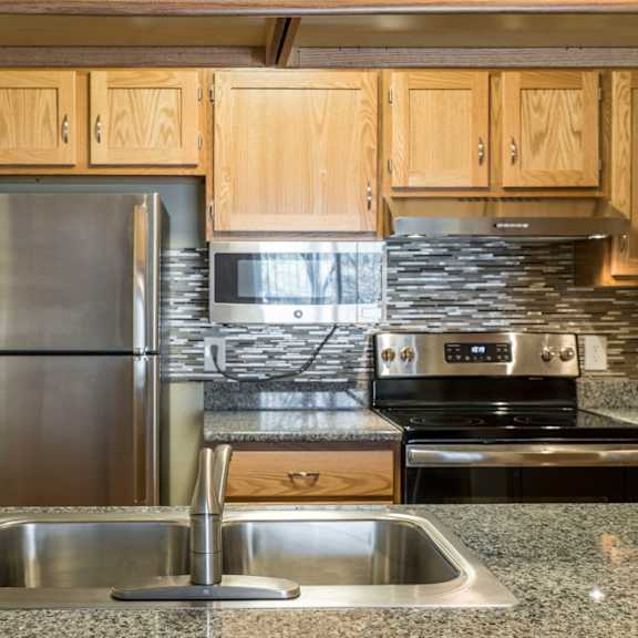 Thumbnail 5 of 12 A kitchen with a stainless steel refrigerator, microwave, oven, and sink.