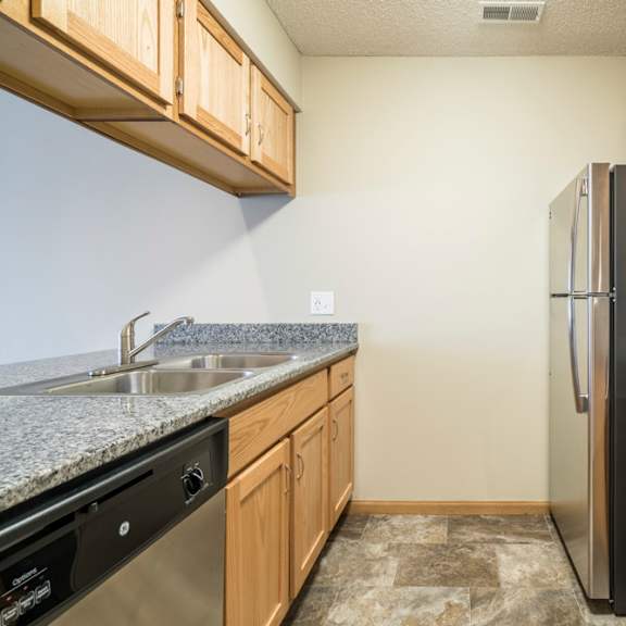 Thumbnail 8 of 12 A kitchen with wooden cabinets and granite countertops.