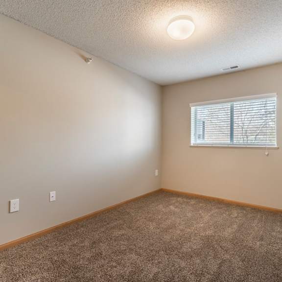 Thumbnail 11 of 12 A room with a carpeted floor and a window with blinds.