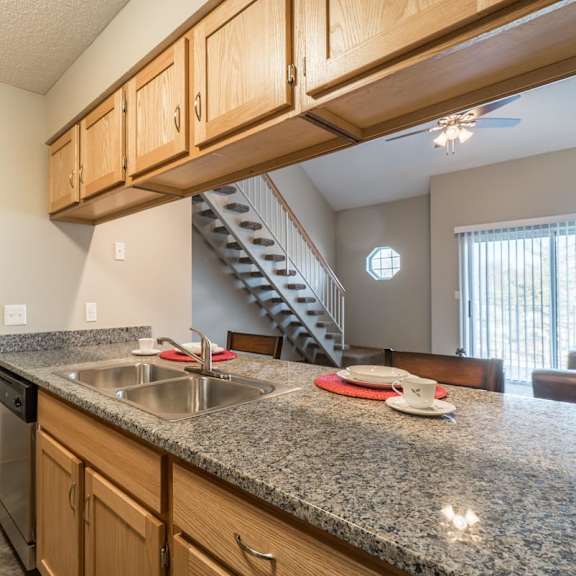 Thumbnail 8 of 16 A kitchen with granite countertops and wooden cabinets.