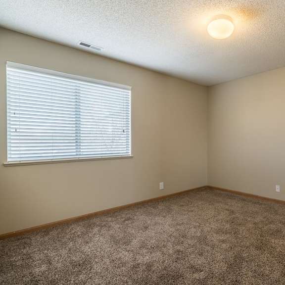 Thumbnail 16 of 16 A room with a carpeted floor and a window with blinds.