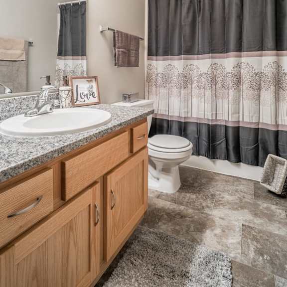 Thumbnail 11 of 16 A bathroom with a sink, toilet, and shower curtain.