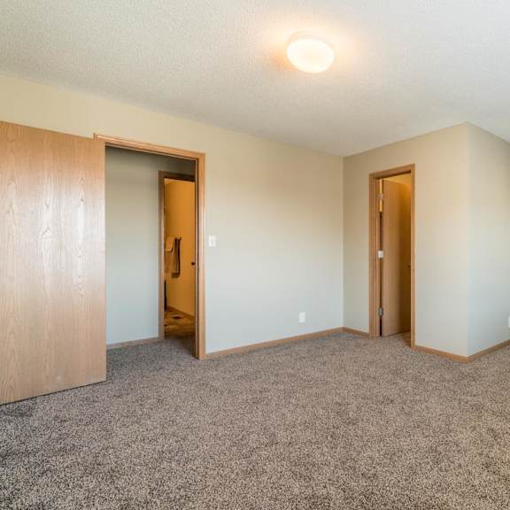 Thumbnail 10 of 16 A room with carpeted floor and two doors.