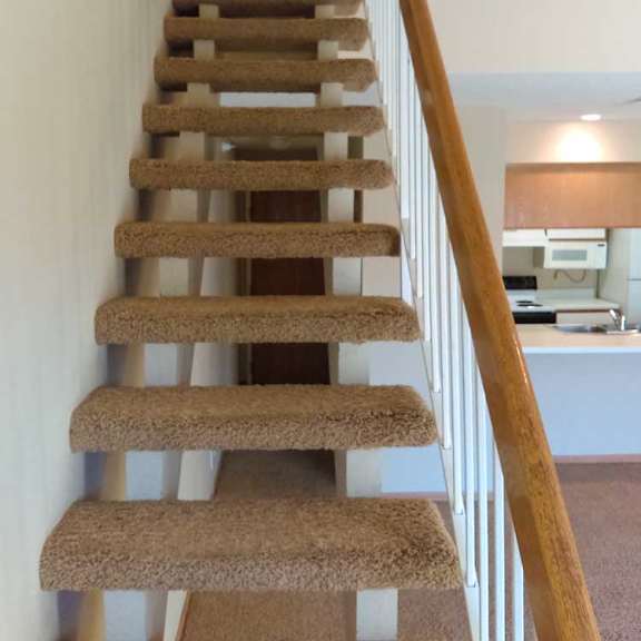 Thumbnail 20 of 24 a carpeted staircase with a wooden handrail