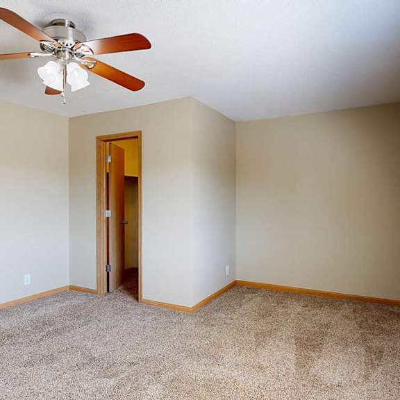 Thumbnail 25 of 27 Spacious carpeted bedroom with neutral walls, ceiling fan with light, and doorway access to hallway and walk-in closet.