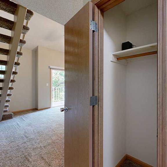 Thumbnail 4 of 27 Coat closet with hanging rod and upper shelf, located near the staircase and living area.