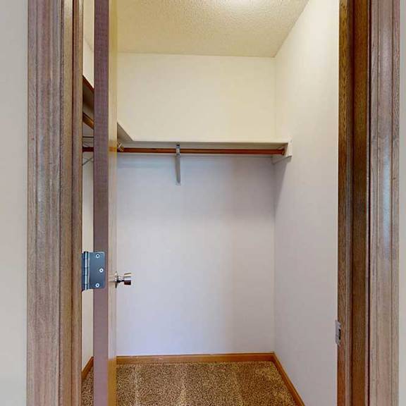 Thumbnail 16 of 27 Walk-in closet with carpet flooring, wraparound hanging rods, and upper shelf for organized storage.
