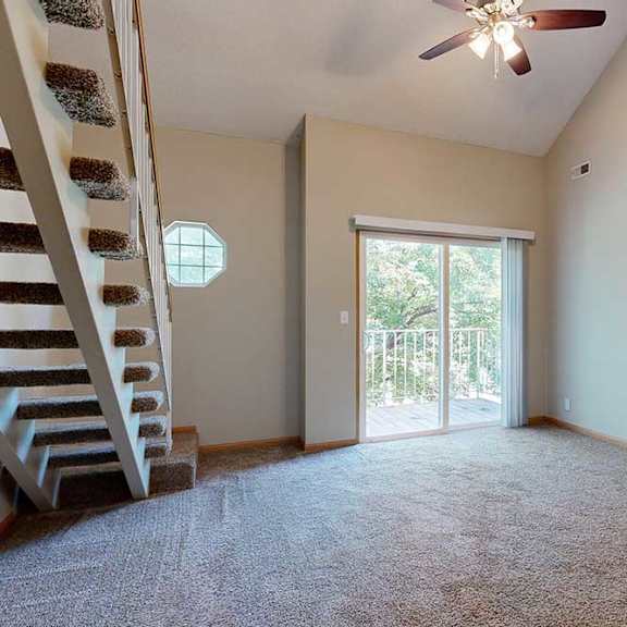 Thumbnail 10 of 27 Two-story living area with vaulted ceiling, ceiling fan, sliding glass door to balcony, and open staircase to loft.