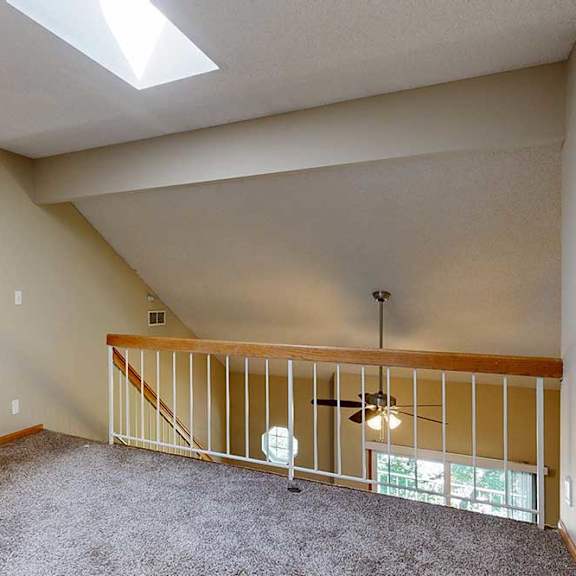 Thumbnail 22 of 27 Loft landing with carpet, wood-trim railing, and view of ceiling fan and balcony below.