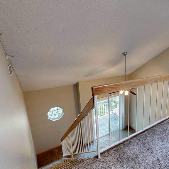 Thumbnail 21 of 27 Loft landing with carpet, wood-trim railing, and view of ceiling fan and balcony below.