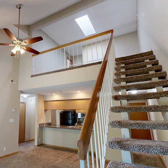 Thumbnail 20 of 27 Open staircase with carpeted steps and white railing leading to loft, overlooking the living room and kitchen.