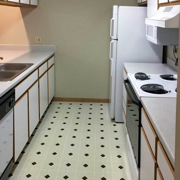 Thumbnail 4 of 11 a kitchen with white and brown cabinets, white appliances, and vinyl flooring