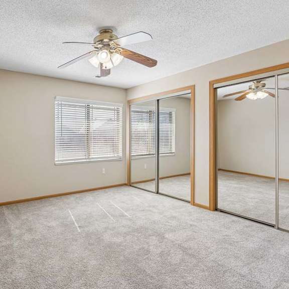 Thumbnail 35 of 38 Spacious bedroom with mirrored closet doors, carpet flooring, and ceiling fan.