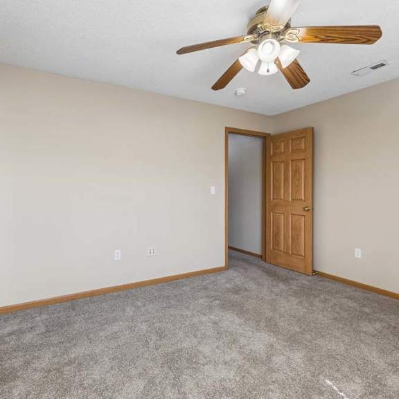 Thumbnail 33 of 38 Bright carpeted bedroom with neutral walls, ceiling fan, and wood trim accents.