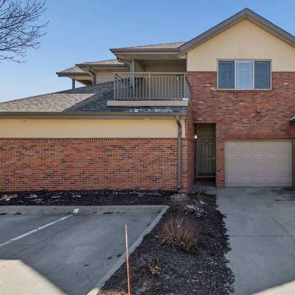 Thumbnail 28 of 38 Exterior view of brick townhome with attached garages and upper balcony.