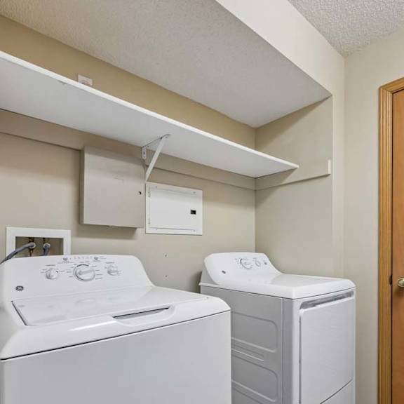 Thumbnail 37 of 38 In-unit laundry area with washer, dryer, and overhead storage shelf.