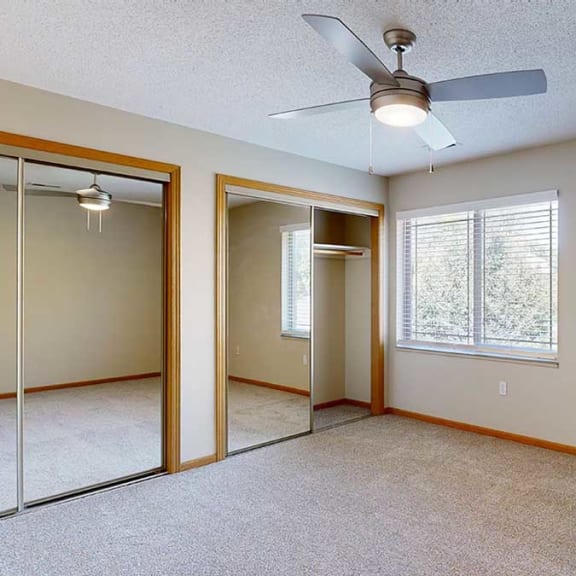 Thumbnail 21 of 26 a bedroom with mirrored closet doors , a ceiling fan, and a large window