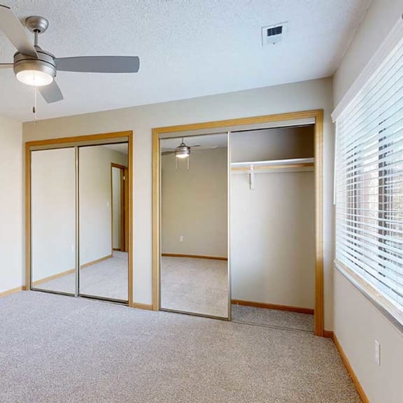 Thumbnail 20 of 26 a bedroom with a ceiling fan and two closets with mirrored doors