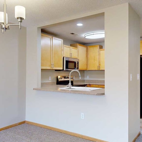 Thumbnail 13 of 26 a kitchen with wooden cabinets and a countertop that opens to the living room