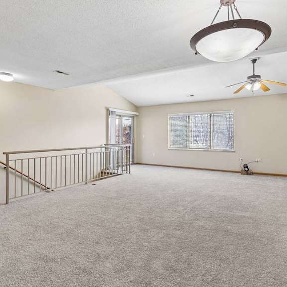 Thumbnail 6 of 17 Spacious upstairs loft with carpeted floors and stairway railing.