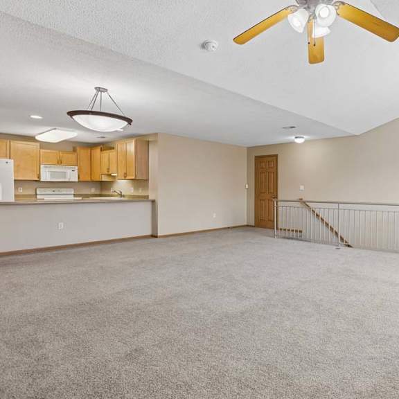 Thumbnail 8 of 17 Open upper-level living area with carpeted floors, ceiling fan, railing overlook, and balcony access.