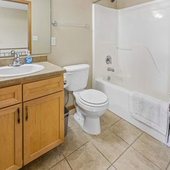 Thumbnail 22 of 29 A bathroom with a white toilet, sink, and bathtub.