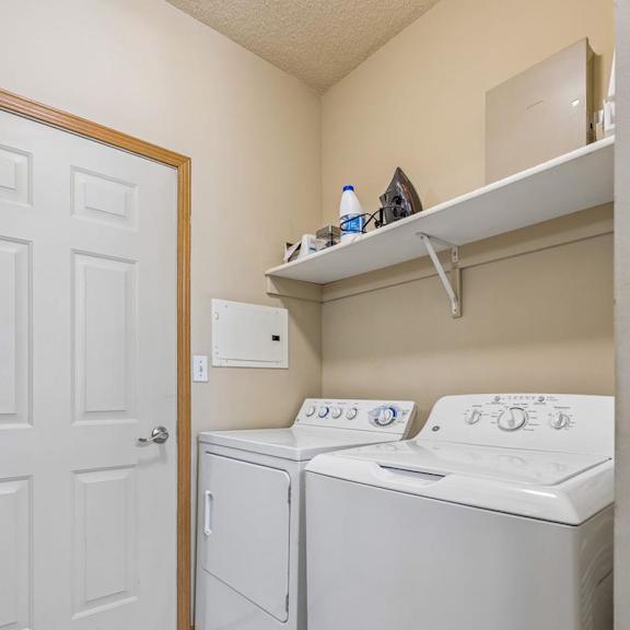 Thumbnail 12 of 29 partment laundry room with full-size washer and dryer, shelving, and additional storage space.