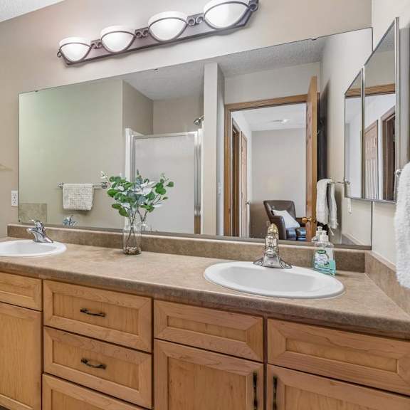 Thumbnail 19 of 29 A bathroom with a white toilet and dual sinks