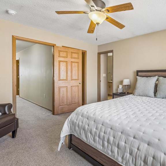 Thumbnail 17 of 29 A bedroom with a large bed, a ceiling fan, and a nightstand with a lamp.