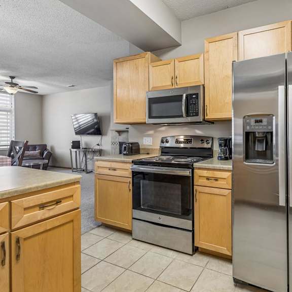 Thumbnail 10 of 29 A kitchen with a stainless steel refrigerator and wooden cabinets.
